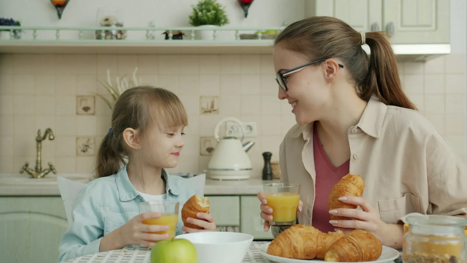 Madre e hija desayunando juntas en una cocina luminosa